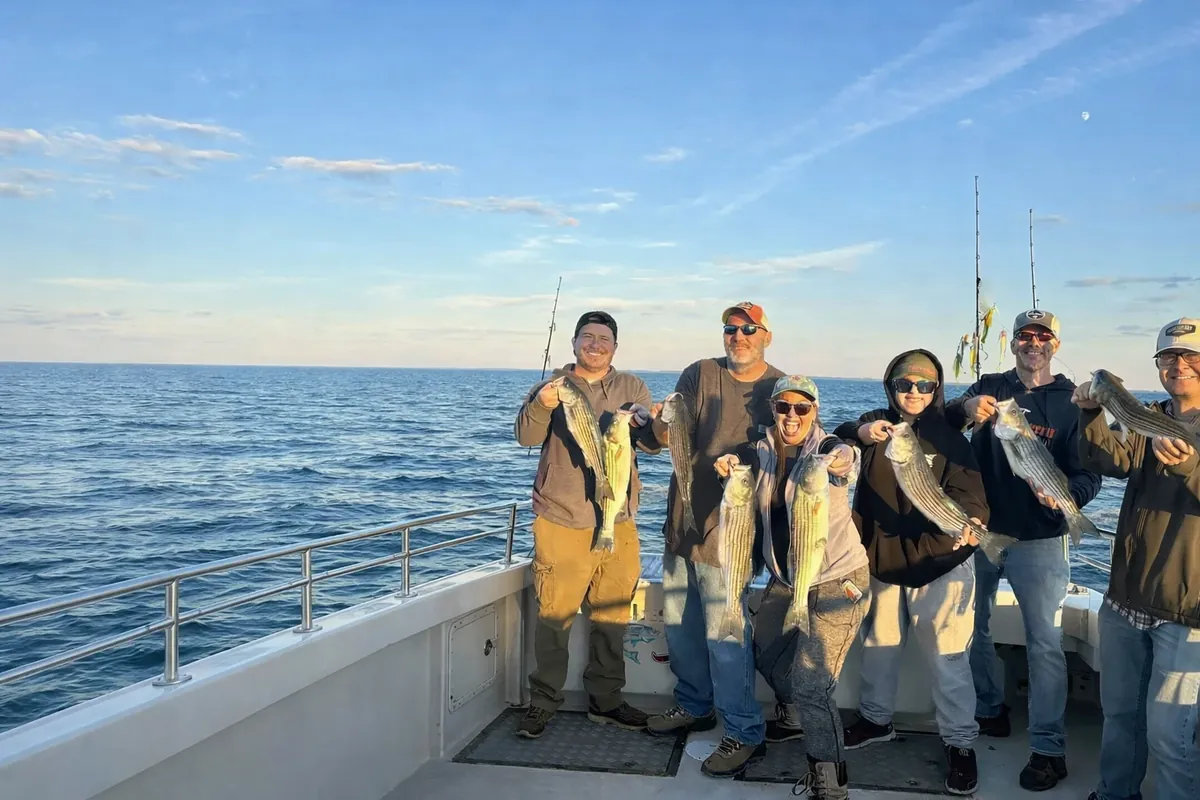 Charter anglers holding striped bass together on deck