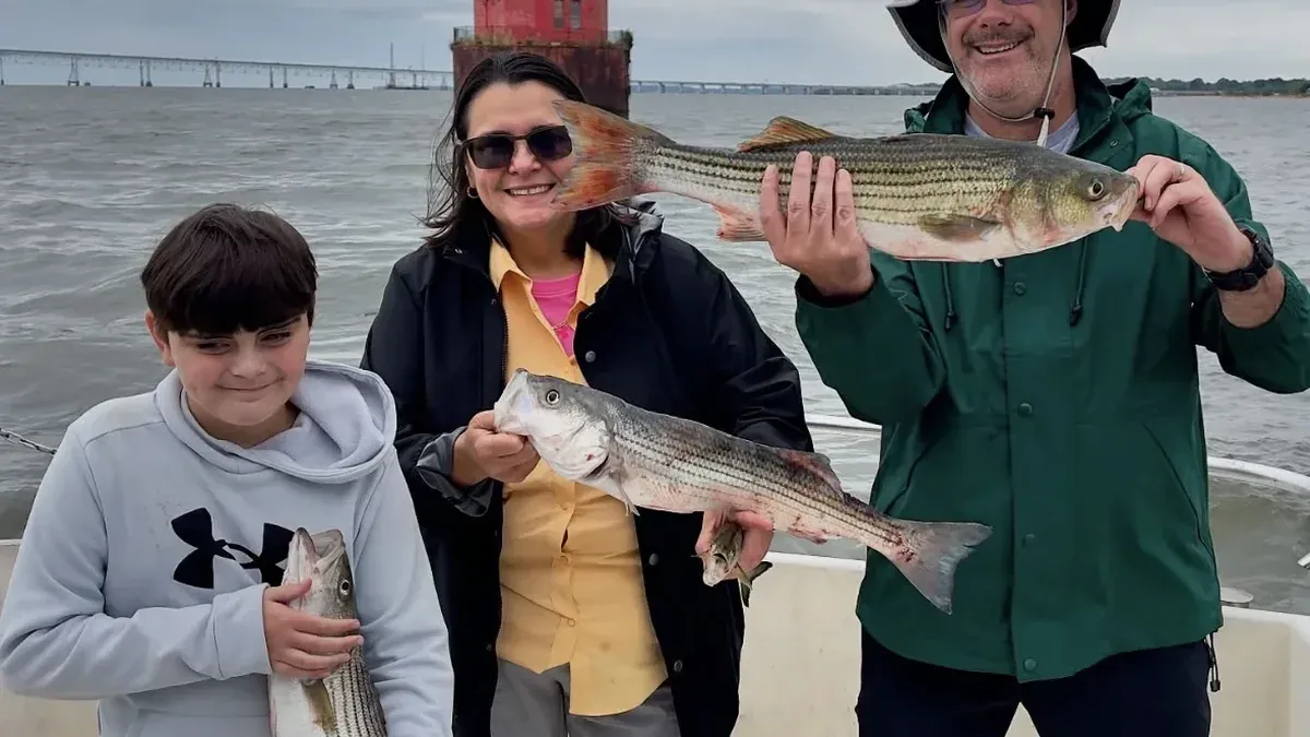 Family displaying striped bass caught on a private charter