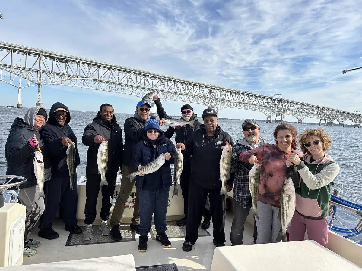 Walk-on anglers holding striped bass after a charter
